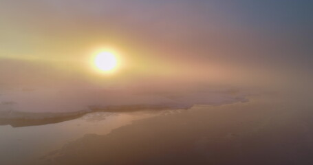 Aerial fly over sunrise fog sky in Antarctica. Morning sun shine through clouds on snow covered...
