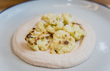 Tasty bean porridge with cauliflower and vegetables on white plate