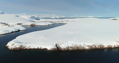 Untouched wilderness of Antarctica winter landscape. Desert white land of snow, cold ocean river, mountains in background. Expeditions and adventures, travel to South Pole. Cinematic drone