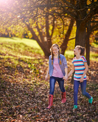 Fototapeta premium Holding hands, happy and children friends in nature walking on adventure together in Autumn. Smile, fun and girl kids exploring in outdoor park, field or garden for bonding on weekend trip in Canada.