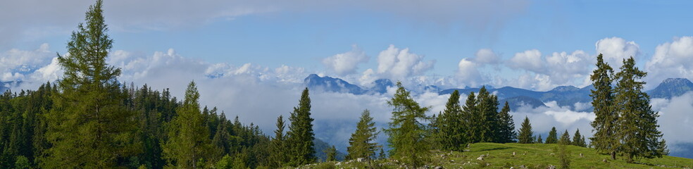 Panorama über einer Alm in den Alpen mit aufsteigenden Wolken