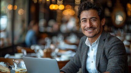 Smiling man with curly hair working on a laptop at a stylish cafe