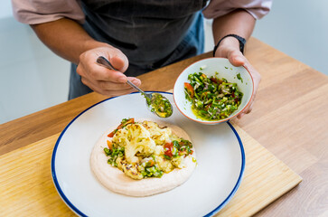 Chef at the kitchen preparing bean porridge with cauliflower and vegetables