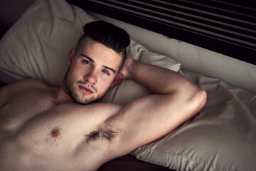 Portrait, chest and body of man on bed for relax with weekend break, confidence and pillow for rest. Topless, sexy and male person on mattress in home with skin for lazy Sunday, muscle and wellness