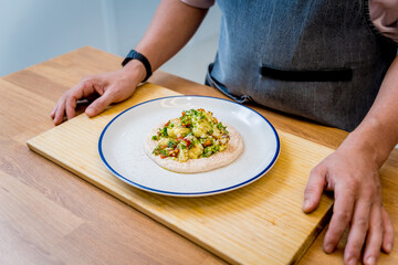 Chef at the kitchen preparing bean porridge with cauliflower and vegetables