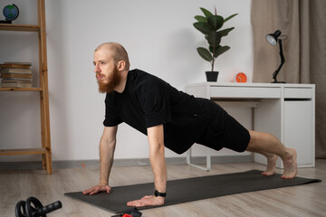 A man is doing yoga plank at home on a mat to get fit in a peaceful environment