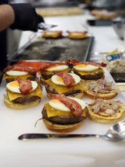 make burgers with ingredients fried egg, meat, melted cheese and bacon on brioche bun