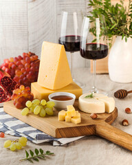 Elegant cheese board featuring a variety of cheeses, grapes, and accompaniments, paired with glasses of red wine