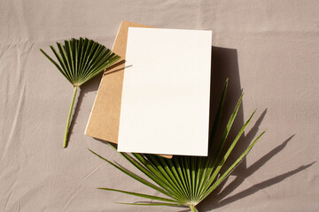 Empty writing notebook and palm leaf on a gray background with contrasting shadows. Lifestyle. Flat Lay