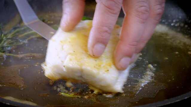 White fish pike-perch, zander are fried in a pan in hot olive oil. The cook flips the white fish fillet over to the other side, with the fried part facing up. 4k slow motion 100 fps footage.