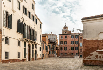 Row of buildings on cobblestone street in city, with sky and clouds above