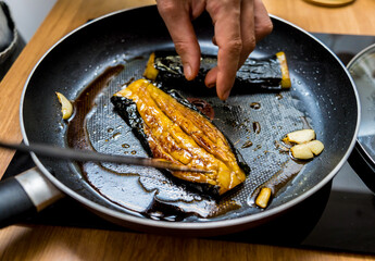 Chef at the kitchen preparing grilled eggplants with garlic