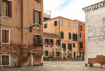 Row of buildings on cobblestone street in city, with sky and clouds above