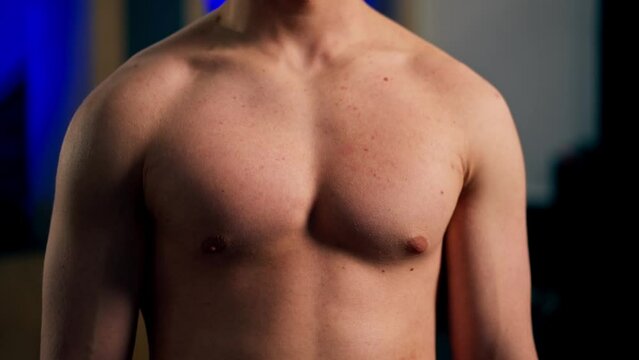 close-up In the gym young handsome trainer works the pectoral muscles of the chest