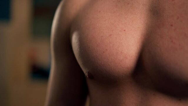 close-up In the gym young handsome trainer works the pectoral muscles of the chest