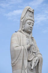 Giant white Guan Yin statue at Guanyin Bodhisattva Pavilion in Kanchanaburi, Thailand. Beautiful Chinese goddess sculpture against blue sky, famous religious landmark for tourism.