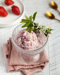 Homemade strawberry ice cream served in an glass bowl, garnished with fresh strawberry slices