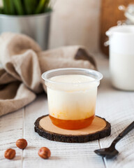 Yogurt or panna cotta with apricot jam in a clear plastic cup. Dairy product