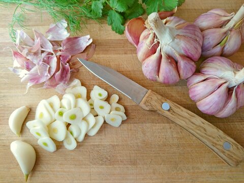 Garlic sliced & red garlic bulb, cloves on wooden background. Concept healthy organic purple cut garlic - eating superfood on rustic wood kitchen chopping board. Garlic chopped food smell ingredient