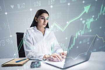 A focused businesswoman analyzes financial graphs projected over her workspace with a modern laptop, concept of data analysis
