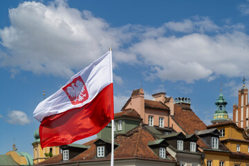 Polska flaga na tle dachów domów  Strego Mista na Placu Zamkowym w Warszawie. © jarizPJ