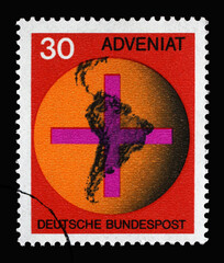Stamp printed in Germany showing Cross in front of a globe with map of South America, “Adveniat,” aid movement of German Catholics for the Latin American church, circa 1967