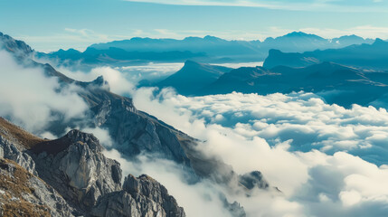 Fototapeta premium A serene mountainous scene with rocky peaks and valleys shrouded in clouds under a clear sky