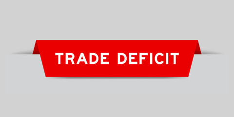 Red color inserted label with word trade deficit on gray background