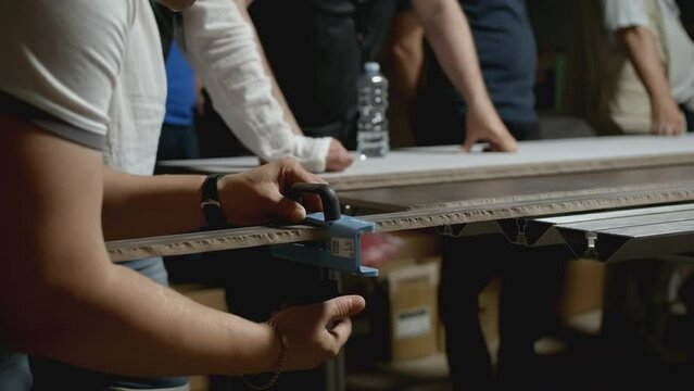 Woodworking master class. Creative. Close-up of man shows group of people how to take measurements on wooden board. Master class in carpentry in industrial workshop