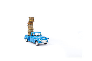 Die cast pickup toy carrying  a high stack of coins, isolated on white background, soft focus close...