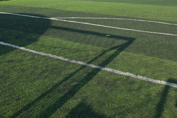 artificial green grass turf sport soccer field with black rubber granules infill and shadow of football goal