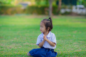Happy asian little girls sitting and post pay respect on the park