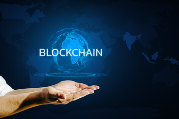 A digital globe floating above a hand with the word BLOCKCHAIN illuminated, set against a blue...