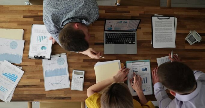 Team of colleagues is working on new startup project in office with documents and laptop top view. Collaboration and brainstorming business development