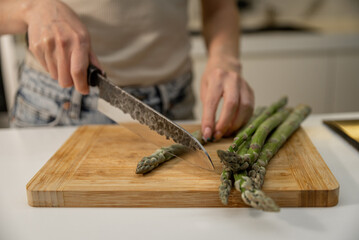 Woman cutting asparagus on wooden board