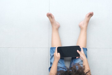 a girl with curly hair plays a smartphone on the terrace of the house