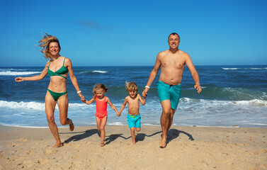 Parents and kids hold hands on beach run with carefree smile