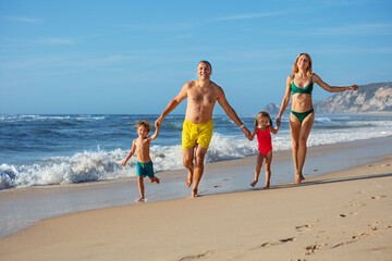 Playful kids lead laughing parents in carefree run by ocean edge