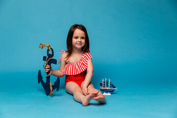 Funny little girl, kid Sailor, ship captain in Striped red swimsuit has fun with steering wheel on...