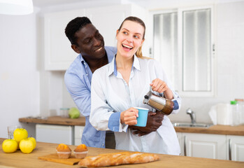 Happy couple preparing coffee and breakfast in kitchen