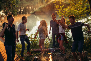 young attractive active tourists are orginizing an open air disco near the lake. party concept. dance till morning