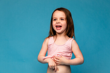 Happy little girl in a pink swimsuit laughs cheerfully. Mockup. Isolated blue background. Summer...