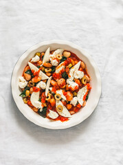 Cooking delicious snack, appetizer, tapas - baked beans with spinach and mozzarella on a light background, top view