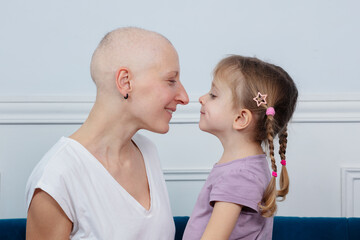 Bald mother recovering from cancer touch noses with her daughter