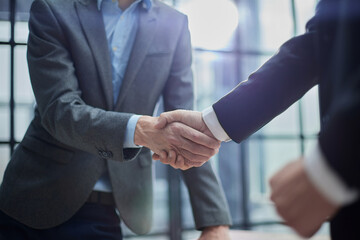 Two diverse professional business men executive leaders shaking hands at office meeting