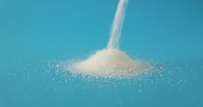 White sugar is poured on table on blue background. Technology for production of sugar from sugar beet and cane
