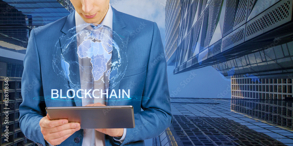 Poster a man in a blue suit holding a tablet with a blockchain concept graphic, standing against a modern b
