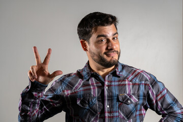 Hombre modelo haciendo el numero 3 con su mano. Fotografía de estudio con fondo blanco