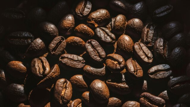 An overhead shot of coffee beans being freshly roasted Moody side lighting creating high contrast on the beans' textures