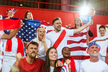 American sport fans cheering at the stadium with flags and other equipment.